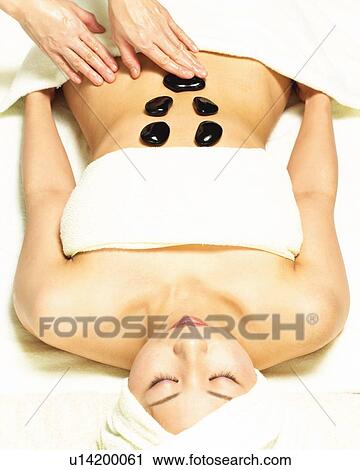 Stock Image - Aesthetician Who Pushes Woman's Stomach With Stones, High Angle View. Fotosearch