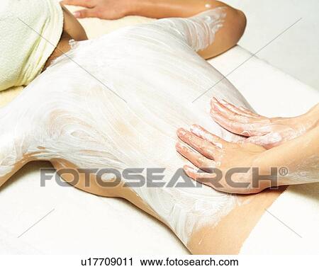 Stock Image - Aesthetician Who Rubs Cream on Woman's Back, High Angle View. Fotosearch