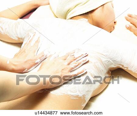 Stock Photo - Aesthetician Who Rubs Cream on Woman's Back, High Angle View. Fotosearch