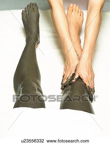 Stock Image - Aesthetician Who Rubs Mud Pack on Woman's Leg, High Angle View. Fotosearch