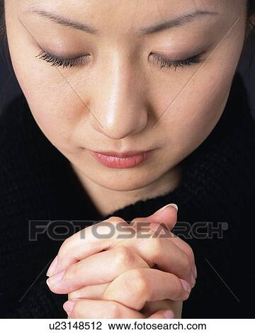 Stock Image - Praying Young Woman, High Angle View, Close Up. Fotosearch