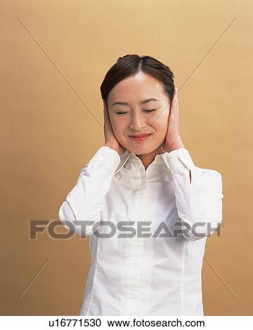 Stock Image - Young Woman Blocking Ears, Front View. Fotosearch