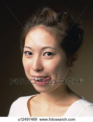 Stock Photo - Young Woman Putting Her Tongue Out, Side View, Looking at Camera. Fotosearch