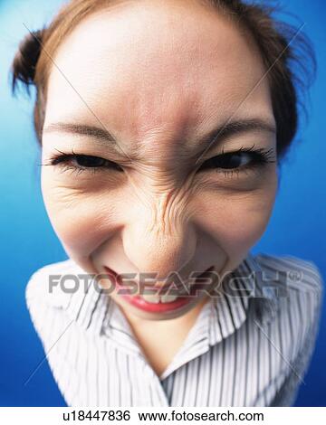 Stock Photograph - Young Woman Wrinkling Up Her Nose, High Angle View, Close Up, Looking at Camera, Fish-eye. Fotosearch