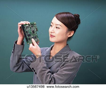 Businesswoman holding and looking at electrical part, Studio, Portrait View Large Photo Image Stock Photo - Businesswoman holding and looking at electrical part, Studio, Portrait. Fotosearch