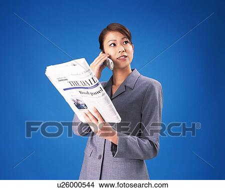 Businesswoman holding news paper and talking on mobile, Studio, Portrait View Large Photo Image Picture - Businesswoman holding news paper and talking on mobile, Studio, Portrait. Fotosearch
