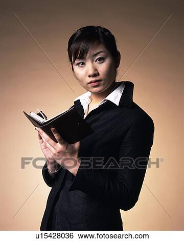 Stock Photograph - Businesswoman holding organizer in hands, Studio, Portrait. Fotosearch