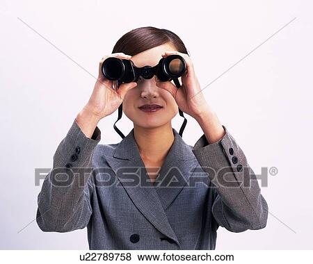 Stock Photo - Businesswoman looking at something with a pair of binoculars, Studio, Portrait. Fotosearch