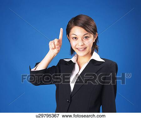 Stock Photo - Businesswoman pointing up with index finger, Studio, Portrait. Fotosearch