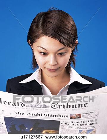 Stock Photo - Businesswoman reading news paper, Studio, Portrait. Fotosearch