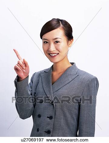 Stock Photo - Businesswoman smiling and pointing index finger, Studio, Portrait. Fotosearch