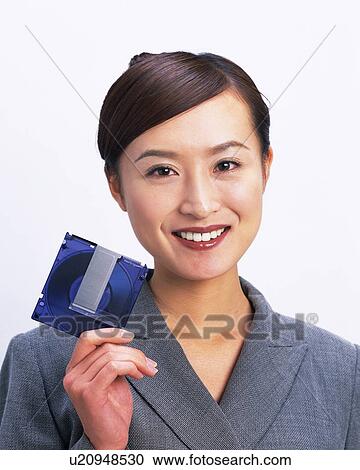 Stock Image - Businesswoman smiling at camera with MO disc, Studio, Portrait. Fotosearch