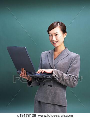 Businesswoman standing and working on laptop computer, Studio, Portrait View Large Photo Image Stock Photo - Businesswoman standing and working on laptop computer, Studio, Portrait. Fotosearch