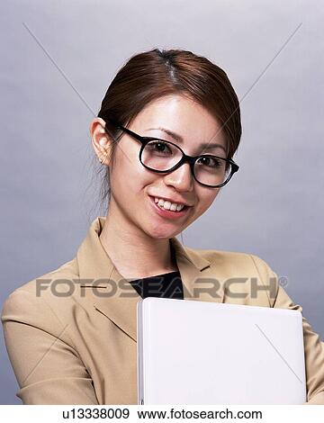 Businesswoman with glasses smiling and holding file, Studio, Portrait View Large Photo Image Stock Photo - Businesswoman with glasses smiling and holding file, Studio, Portrait. Fotosearch