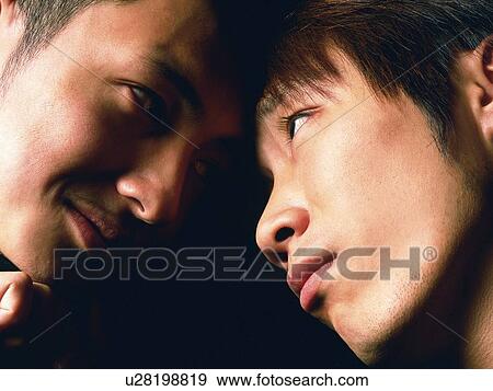 Stock Photo - Group of two young adult men close together and looking at each other, Close Up, Studio. Fotosearch