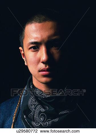 Stock Image - Young adult man looking at camera, studio, Portrait. Fotosearch