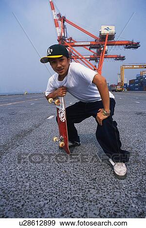 Stock Photo - Young adult man posing with skateboard, Outdoors, Portraint. Fotosearch