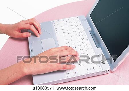 Stock Image - Closed Up Image of a Female Hands, Typing on the Keyboards of a Laptop, High Angle View. Fotosearch