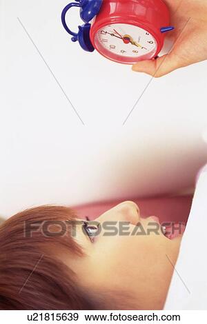 Stock Photo - Closed Up Image of a Young Adult Woman Staring At her clock In Surprise, Side View. Fotosearch