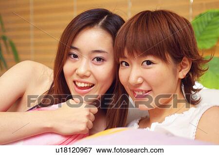 Two Young Adult Woman Sitting, Looking at Camera and Smiling, Front View View Large Photo Image Stock Photo - Two Young Adult Woman Sitting, Looking at Camera and Smiling, Front View. Fotosearch