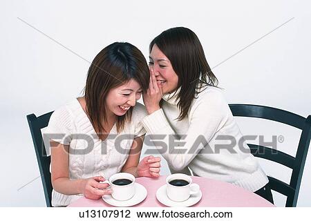 Two Young Adult Women Having Coffee, One Whispering Something in the Other One's Ear, High Angle View View Large Photo Image Stock Image - Two Young Adult Women Having Coffee, One Whispering Something in the Other One's Ear, High Angle View. Fotosearch