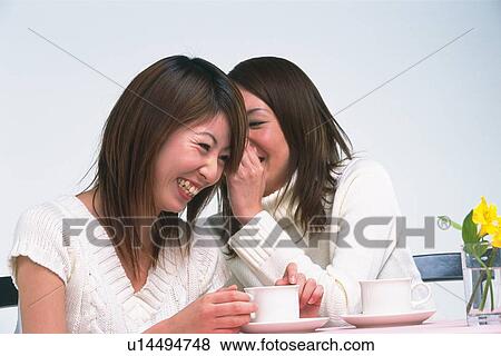 Two Young Adult Women Having Coffee, One Whispering Something in the Other One's Ear, Smiling, Side View View Large Photo Image Stock Photo - Two Young Adult Women Having Coffee, One Whispering Something in the Other One's Ear, Smiling, Side View. Fotosearch