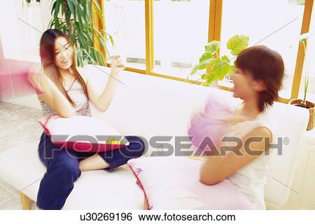 Stock Photograph - Two Young Adult Women Laughing, Talking on a Couch, High Angle View, Blurred Motion. Fotosearch