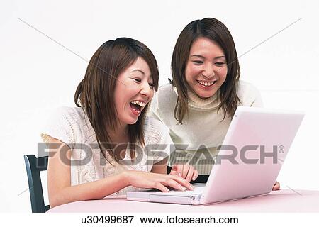 Two Young Adult Women Operating a Laptop on a Desk, Laughing, Side View View Large Photo Image Stock Photo - Two Young Adult Women Operating a Laptop on a Desk, Laughing, Side View. Fotosearch