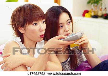 Stock Image - Two Young Adult Women Watching TV, Side View. Fotosearch