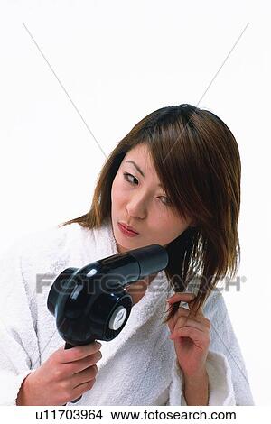 Young Adult Woman Blow Drying her Hair Looking Down, Front View View Large Photo Image Picture - Young Adult Woman Blow Drying her Hair Looking Down, Front View. Fotosearch