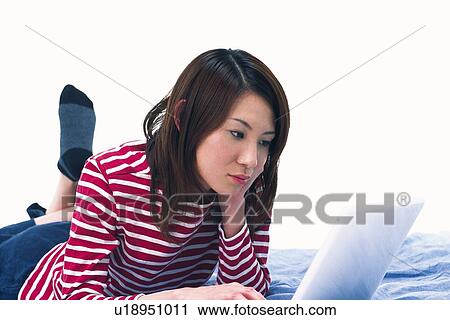 Stock Image - Young Adult Woman Operating a Laptop, Side View, Low Angle View. Fotosearch