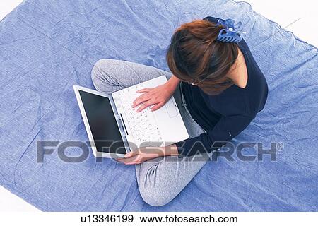 Young Adult Woman Operating her Laptop on a Blue Blanket, High Angle View View Large Photo Image Stock Photo - Young Adult Woman Operating her Laptop on a Blue Blanket, High Angle View. Fotosearch