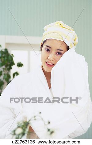 Stock Photograph - Young Woman Drying Her Face With White Bath Towel, Looking at Camera, Low Angle View. Fotosearch