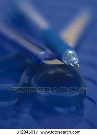 Stock Photo - Close up of pen, paper cutter and scissors in blue. Fotosearch