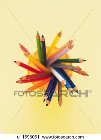 Stock Image - Colored pencils in orange penholder fanned out in a circle. Fotosearch