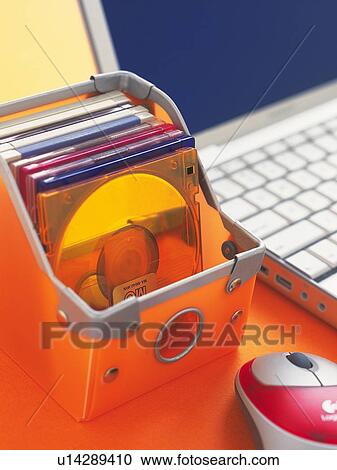 Stock Image - Laptop and colorful MOs in holder on desk. Fotosearch