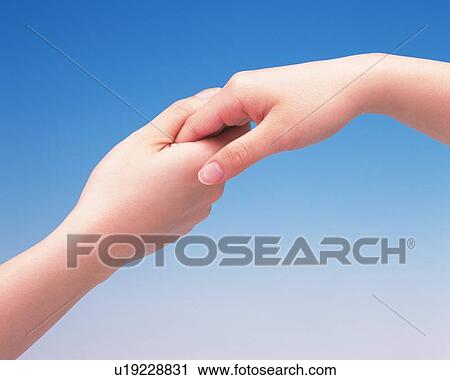 Stock Image - Hand of two women, one holding the other's for support. Fotosearch