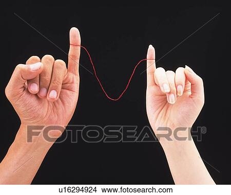 Picture - Woman and man connected by red thread tied around their pinkies. Fotosearch