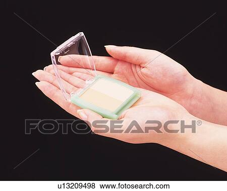 Woman holding a powder compact View Large Photo Image Stock Photo - Woman holding a powder compact. Fotosearch