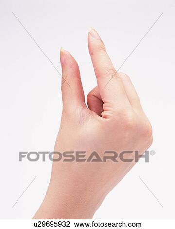 Stock Image - Woman posing of holding something between thumb and forefinger. Fotosearch