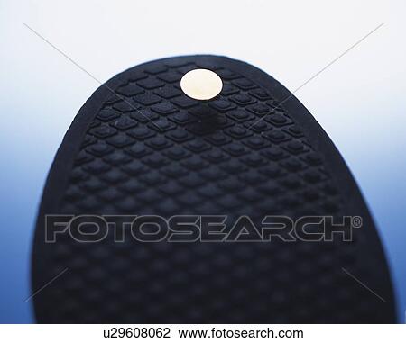 Stock Image - A thumbtack sticking in sole of shoe. Fotosearch