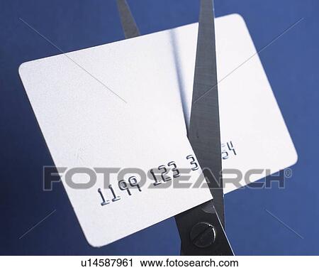 Stock Image - Card being cut by scissors. Fotosearch