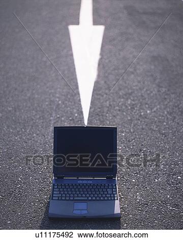 Stock Image - Laptop put on road painted white arrow. Fotosearch