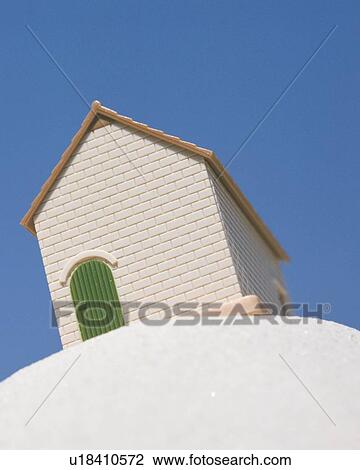 Stock Image - Leaning model of house on white object. Fotosearch
