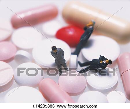 Stock Image - Three male figurines among capsules and tablets. Fotosearch