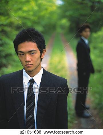 Closed Up Image of a Businessman Standing on a Country Road, Another Businessman in the Background, Looking at Camera, Front View, Side View, Differential Focus View Large Photo Image Stock Photo - Closed Up Image of a Businessman Standing on a Country Road, Another Businessman in the Background, Looking at Camera, Front View, Side View, Differential Focus. Fotosearch