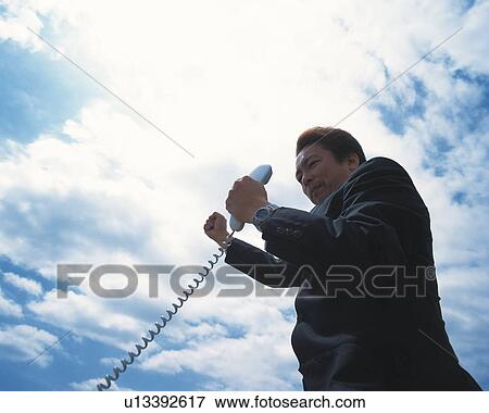 Image of a Businessman Holding a Telephone Receiver Under a Blue Sky, Low Angle View View Large Photo Image Stock Photo - Image of a Businessman Holding a Telephone Receiver Under a Blue Sky, Low Angle View. Fotosearch