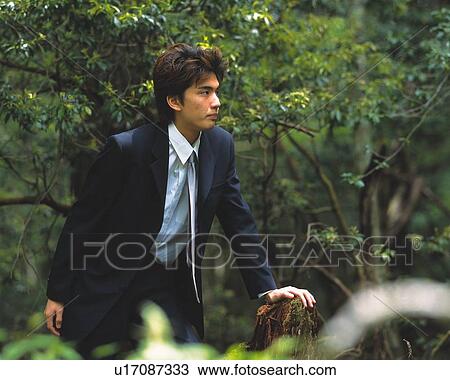 Stock Image - Image of a Businessman Leaning on a Stump in the Forest, Side View. Fotosearch