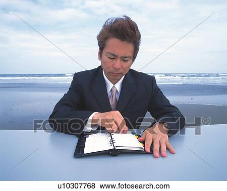 Image of a Businessman Looking at His Appointment Book at the Beach, the Wind Blowing Through his Hair, Front View View Large Photo Image Stock Photo - Image of a Businessman Looking at His Appointment Book at the Beach, the Wind Blowing Through his Hair, Front View. Fotosearch