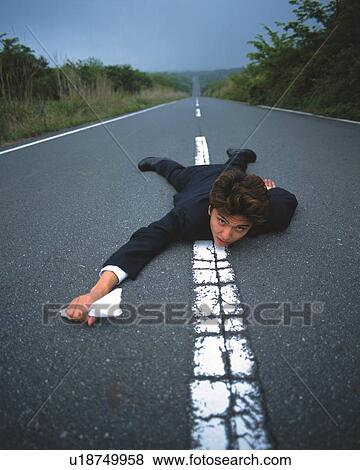 Image of a Businessman Lying on his Stomach in the Middle of a Road, While Holding at Piece of Paper, Looking at Camera, High Angle View View Large Photo Image Stock Photo - Image of a Businessman Lying on his Stomach in the Middle of a Road, While Holding at Piece of Paper, Looking at Camera, High Angle View . Fotosearch